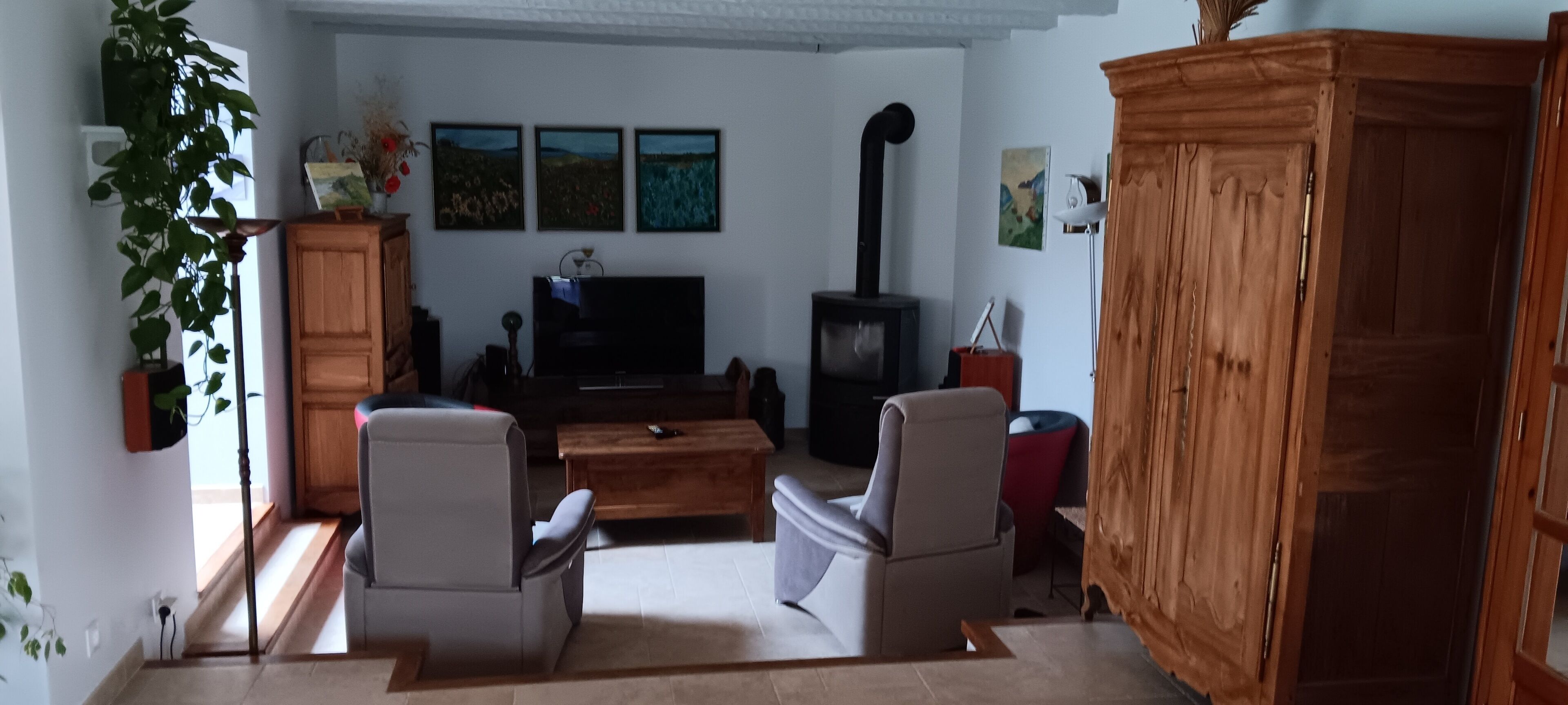 Ein Wohnzimmer mit Kamin, zwei Sesseln, einem Couchtisch und einem Fernseher.