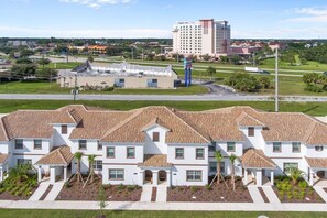 Ein Wohnkomplex mit mehreren zweistöckigen Häusern, einem zentralen Gebäude und einem großen Hotel im Hintergrund.