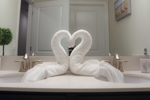 A bathroom with a heart-shaped towel arrangement on the sink.