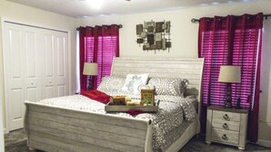 Une chambre à coucher avec un lit, des tables de chevet, une commode et des rideaux.