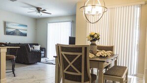 Un coin repas comprenant une table, des chaises, un vase avec des fleurs et un ventilateur de plafond.
