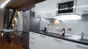 Una cocina moderna con armarios blancos, un refrigerador de acero inoxidable, un microondas y un lavamanos.