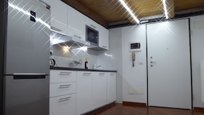 Una cocina moderna con armarios blancos, un microondas integrado y un refrigerador de acero inoxidable.