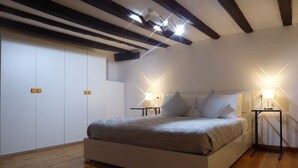Un dormitorio con una cama grande, suelo de madera y techo inclinado con vigas a la vista.