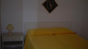 A room with a bed, a nightstand, and a wall-mounted picture frame.