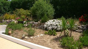 A landscaped garden with various plants and a white decorative structure.
