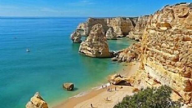 A coastal landscape with rocky cliffs and clear blue waters.