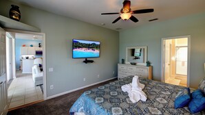 A bedroom with a bed, a ceiling fan, a TV, and a bathroom visible through an open door. - Windsor Hills 2nd Premium 5/5 Lake View Home w/South Pool-Near Disney (Kissimmee)