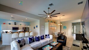 A modern living room with a sofa, coffee table, and a dining area with chairs. - Windsor Hills 2nd Premium 5/5 Lake View Home w/South Pool-Near Disney (Kissimmee)