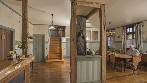 A spacious kitchen with wooden flooring, a central island, and a dining area with wooden chairs and a table. - Estancia 440 Hotel Boutique (Puerto Varas)