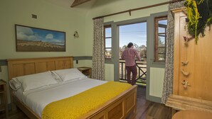 A bedroom with a wooden bed, a large window, and a view of the outdoors. - Estancia 440 Hotel Boutique (Puerto Varas)