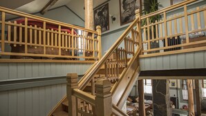 A wooden staircase with a railing, a red bench, and a wall with framed pictures. - Estancia 440 Hotel Boutique (Puerto Varas)