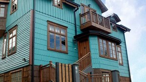 A multi-story building with a distinctive blue exterior, wooden balconies, and traditional window designs. - Estancia 440 Hotel Boutique (Puerto Varas)