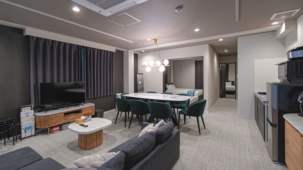 A modern living room with a flat-screen TV, a sofa, a dining table with chairs, and a kitchen area. - INOVE VILLA OSAKA (Osaka)