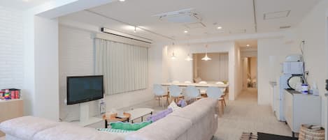 Uma sala de estar moderna com sofá, TV e espaço para refeições.