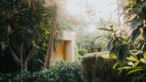 A lush garden with a wooden structure surrounded by dense foliage and a large hay bale. - María & Bernardo Casa - Viñedo (El Marques)