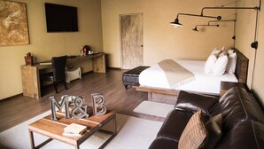 Quarto de hotel com uma cama, uma escrivaninha, um sofá de couro e uma mesa de centro.