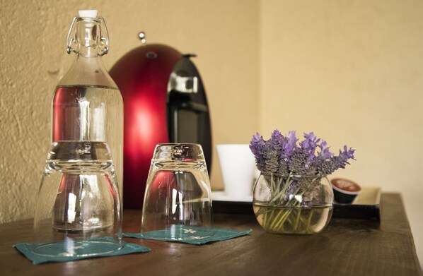 A table with a clear glass bottle, two clear glasses, a red kettle, and a vase with purple flowers. - María & Bernardo Casa - Viñedo (El Marques)