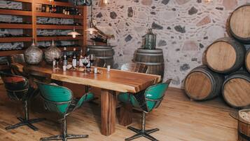 A rustic bar area with wooden furniture, stone walls, and wine barrels.