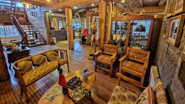 A wooden interior with a staircase, wooden furniture, and a display of pottery.