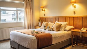 A neatly made bed with a wooden headboard, two bedside lamps, and a telephone on the nightstand.