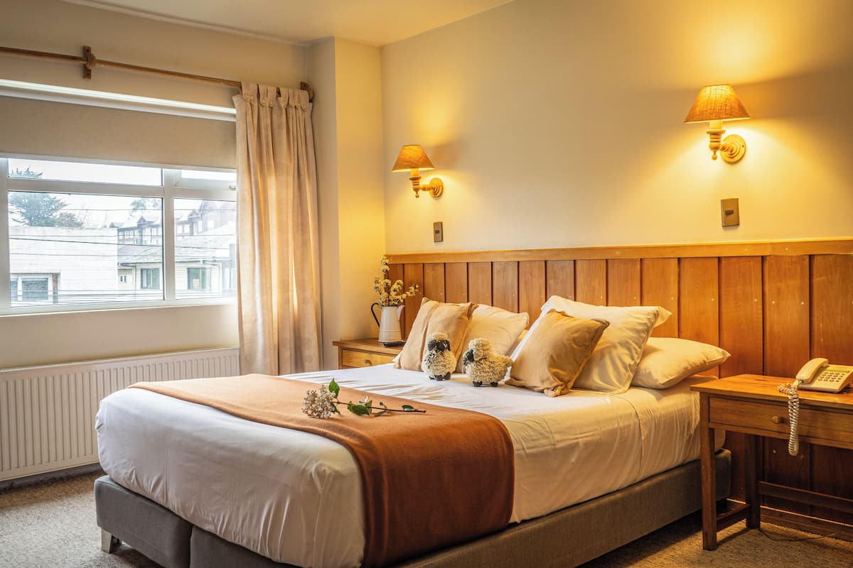 A neatly made bed with a wooden headboard, two bedside lamps, and a telephone on the nightstand.