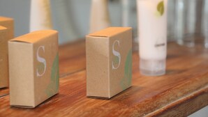 Three cardboard boxes with a logo on a wooden surface.