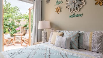 Une chambre à coucher comprenant un lit, une table de chevet, une lampe et donnant sur une terrasse extérieure avec une table et des chaises.