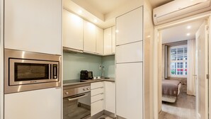 A compact kitchen with a built-in microwave, oven, and a coffee maker on the countertop.