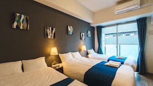 Una habitación de hotel con dos camas, una ventana con cortinas, aire acondicionado y una obra de arte en la pared.
