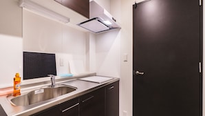 Una cocina moderna con un lavamanos de acero inoxidable, armarios de madera oscura y una puerta negra.