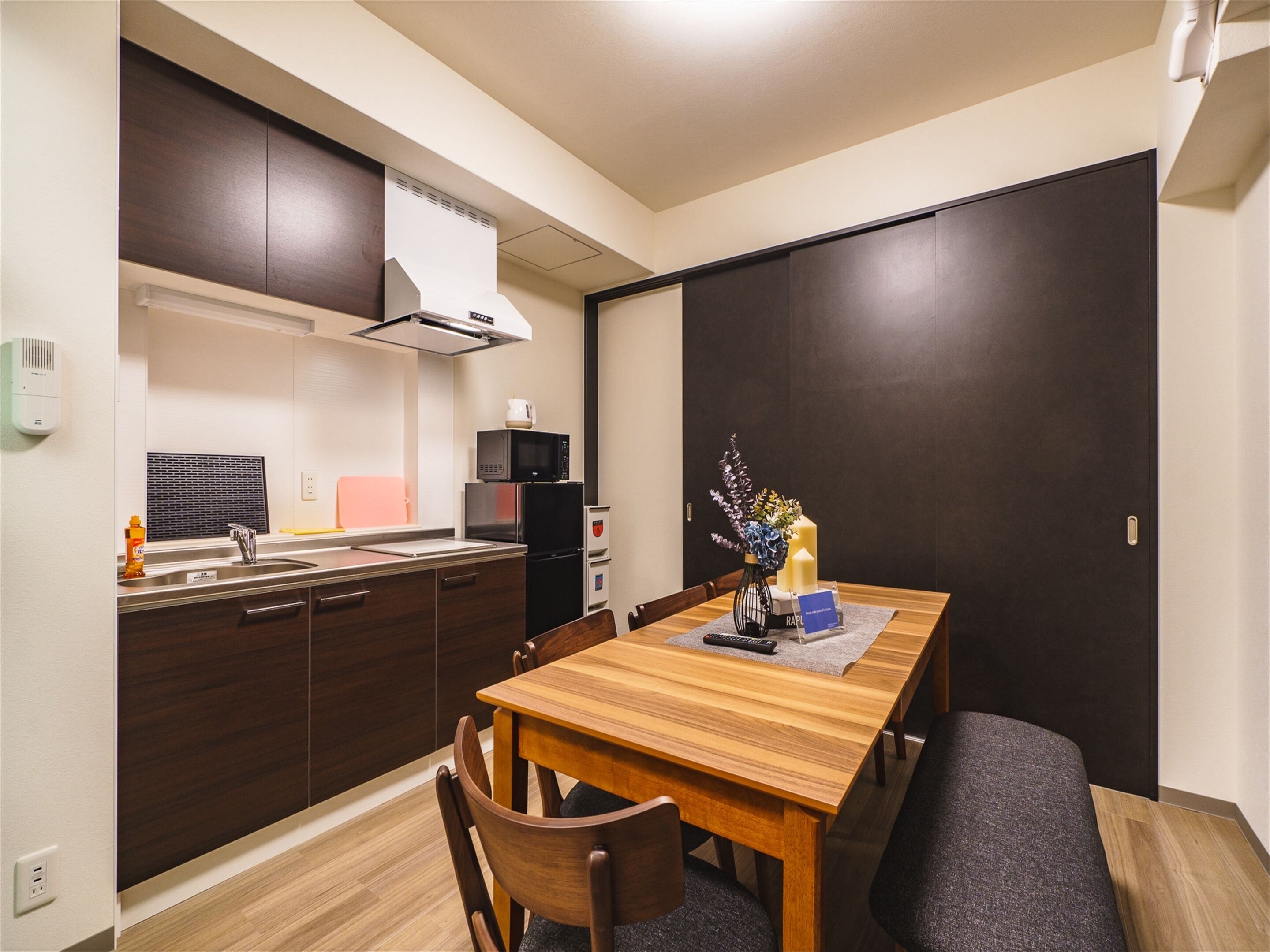 A compact kitchen with a dining area, featuring a microwave, refrigerator, and a small sink.