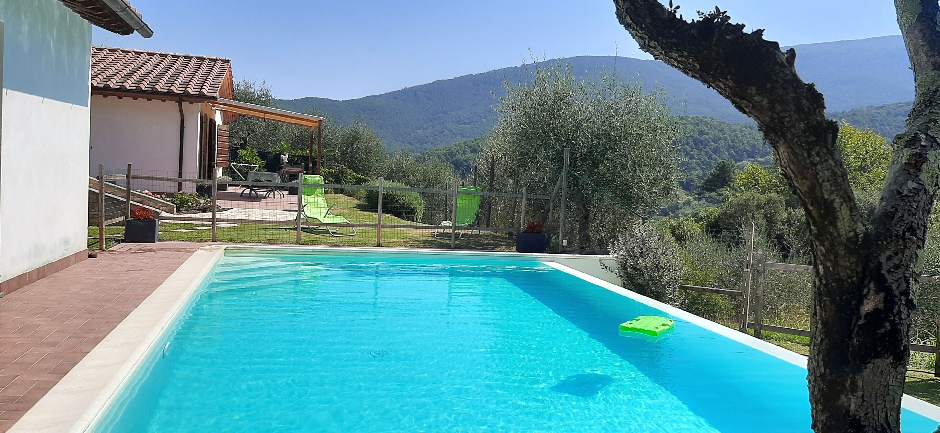 Une piscine avec vue sur les montagnes, un patio couvert et un jardin clos.