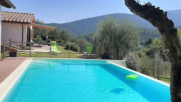 Une piscine avec vue sur les montagnes, un patio couvert et un jardin clos.