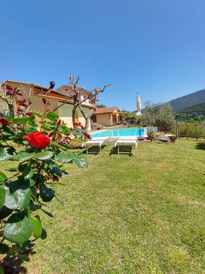 Une piscine, avec une maison en arrière-plan, un ciel dégagé et une montagne à l’horizon.