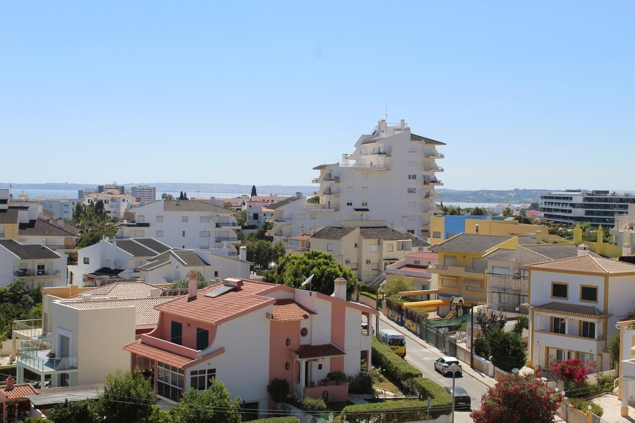 A coastal residential area with a mix of modern and traditional architecture, including a prominent white building with a unique design and a red-roofed house in the foreground.