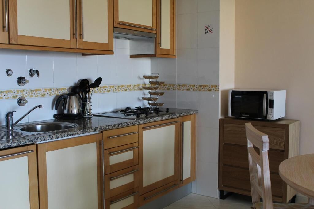 A kitchen with wooden cabinets, a granite countertop, a stove, a sink, and a microwave.