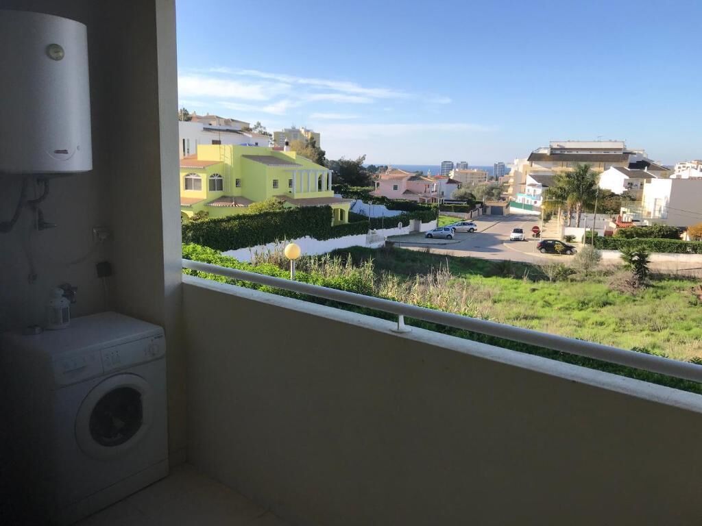 A balcony with a view of a residential area, a washing machine, and a water heater.