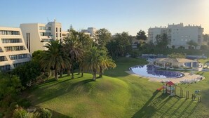 A residential area with modern buildings, a swimming pool, and a grassy park area.