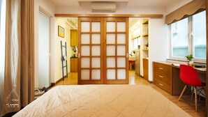 A bedroom with a bed, a desk, and a chair. There is a wardrobe with a sliding door and a window with a view. - Chez Tram Homestay (Hanoi)