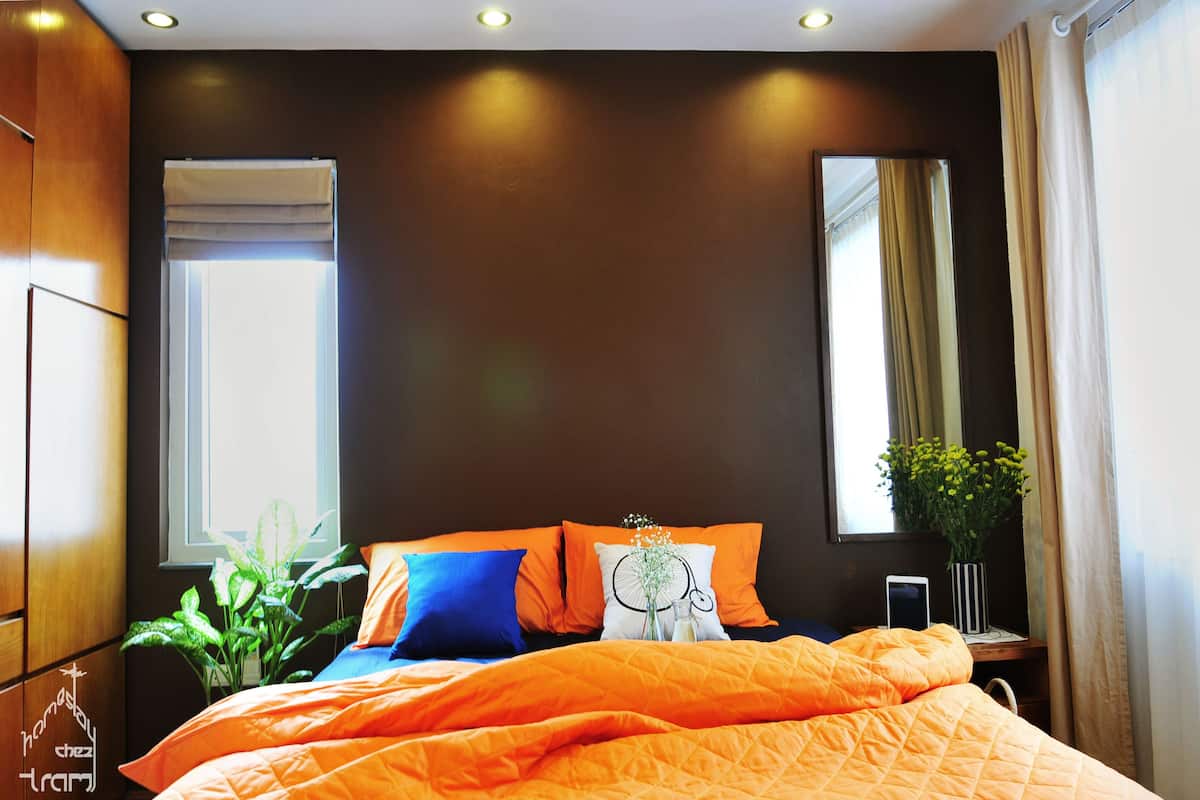 A modern bedroom with a large bed, dark walls, and a window with curtains.