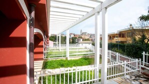 A covered outdoor area with a white fence, a view of buildings, and a stone floor. - S052 - Sirolo, new studio apartment with terrace (Sirolo)