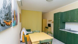 A compact kitchen with green cabinets, a yellow table, and a dining area. - S052 - Sirolo, new studio apartment with terrace (Sirolo)