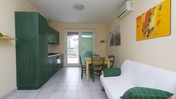 Een knus woongedeelte met een kitchenette, een eethoek en een bank met kussens.
