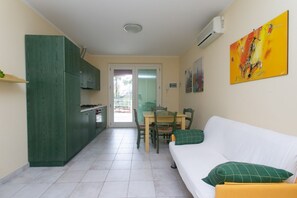 Un espacio habitable compacto con kitchenette, comedor y sofá con cojines.