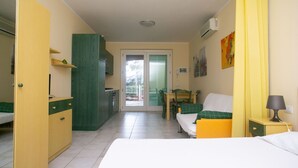A room with a bed, a desk, a chair, a small kitchenette, and a balcony. - S052 - Sirolo, new studio apartment with terrace (Sirolo)