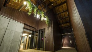 A corridor with a high ceiling, wooden beams, and hanging greenery. There are doors labeled with numbers and a carpeted floor. - Lucky Apple Hotel (Taipei)