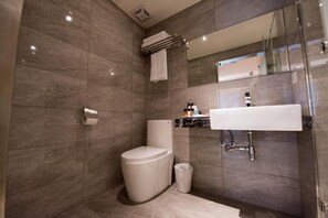 A modern bathroom with a toilet, sink, and mirror. - Lucky Apple Hotel (Taipei)