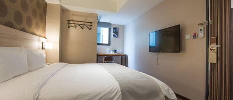 Una habitación de hotel con una cama grande, un escritorio con silla, un televisor montado en la pared y una puerta con diseño a rayas.