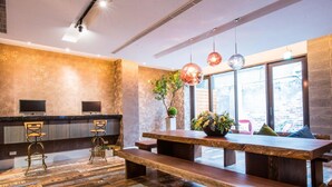 A modern kitchen with a wooden countertop, two bar stools, a wooden bench, and pendant lights. - Lucky Apple Hotel (Taipei)